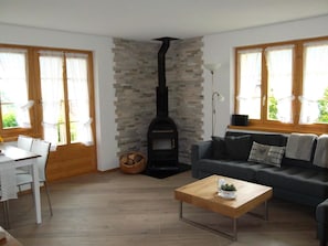 A living room with a fireplace, a sofa, a coffee table, and a dining area with chairs. - Hubertus A Appartement/Fewo 3-Bettwohnung by Interhome (Habkern)