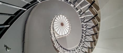 Un escalier en colimaçon doté d’un motif circulaire central et de rampes en métal.