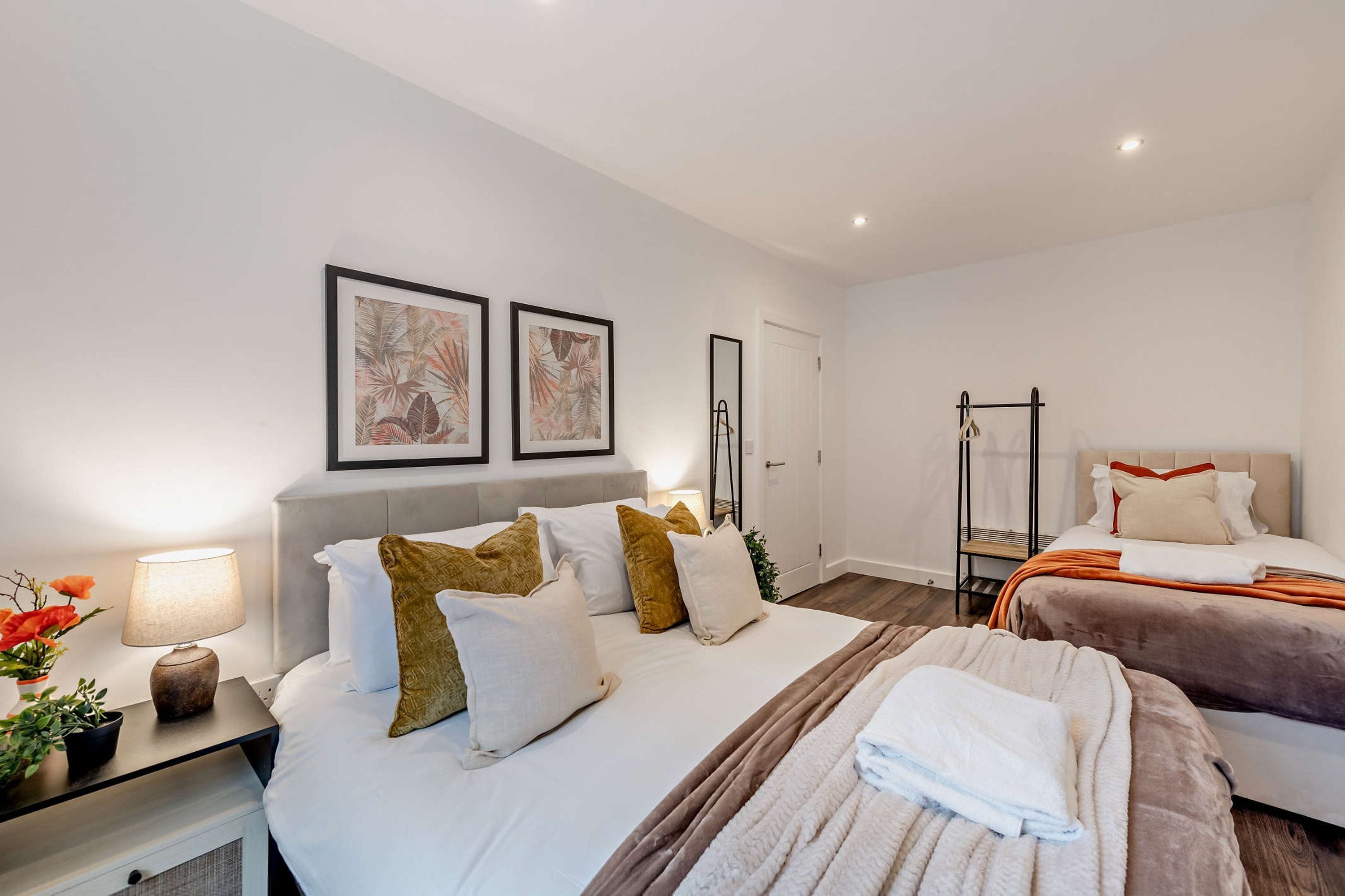 Una habitación de hotel moderna con una cama grande, una mesita de noche con una lámpara y dos cuadros en la pared.