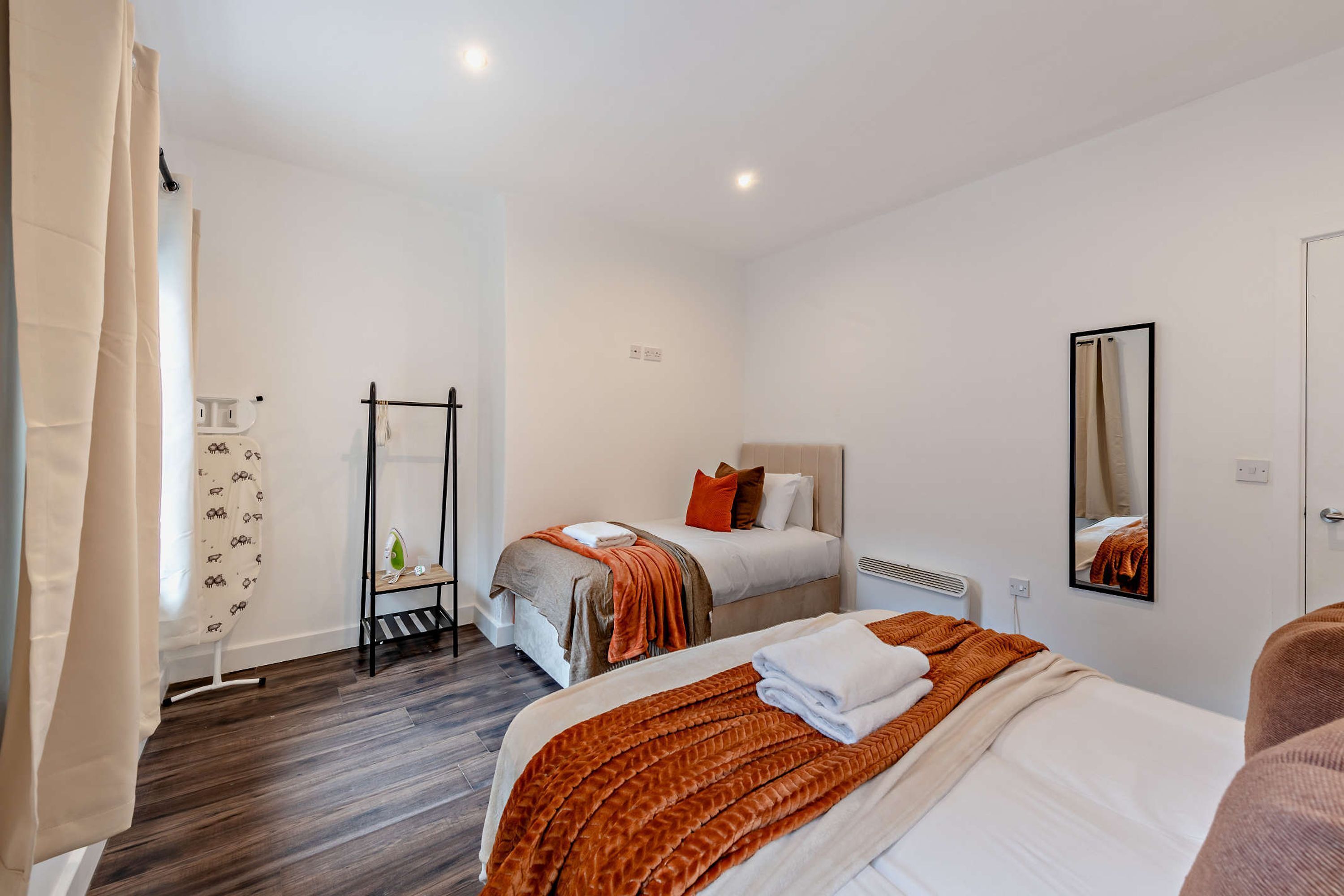 Une chambre d’hôtel avec deux lits, un miroir, un radiateur et un porte-serviettes.
