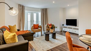 Uma sala de estar moderna com sofá, poltrona, mesa de centro e televisão.