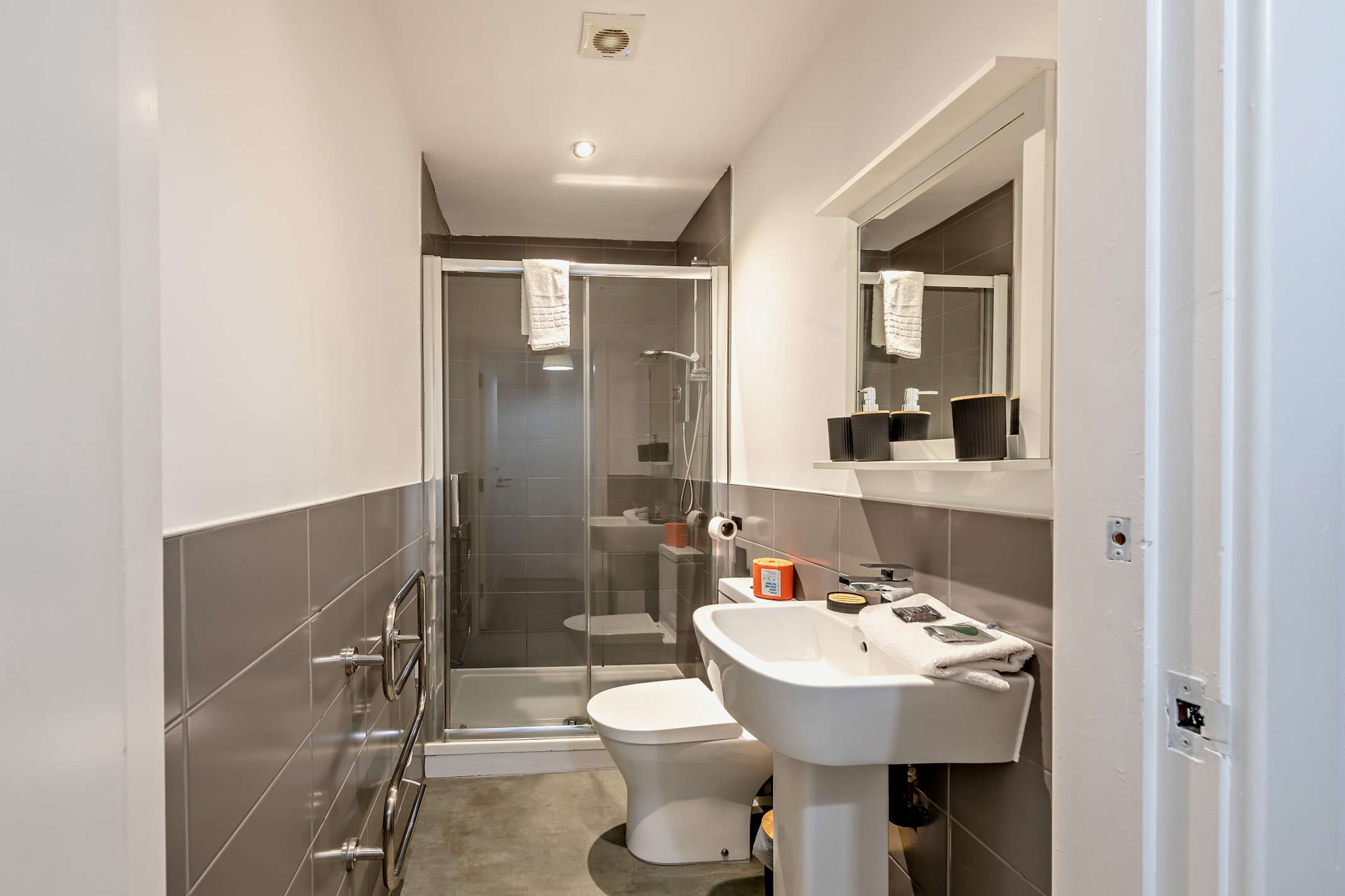 A modern bathroom with a glass-enclosed shower, a white sink, and a toilet.