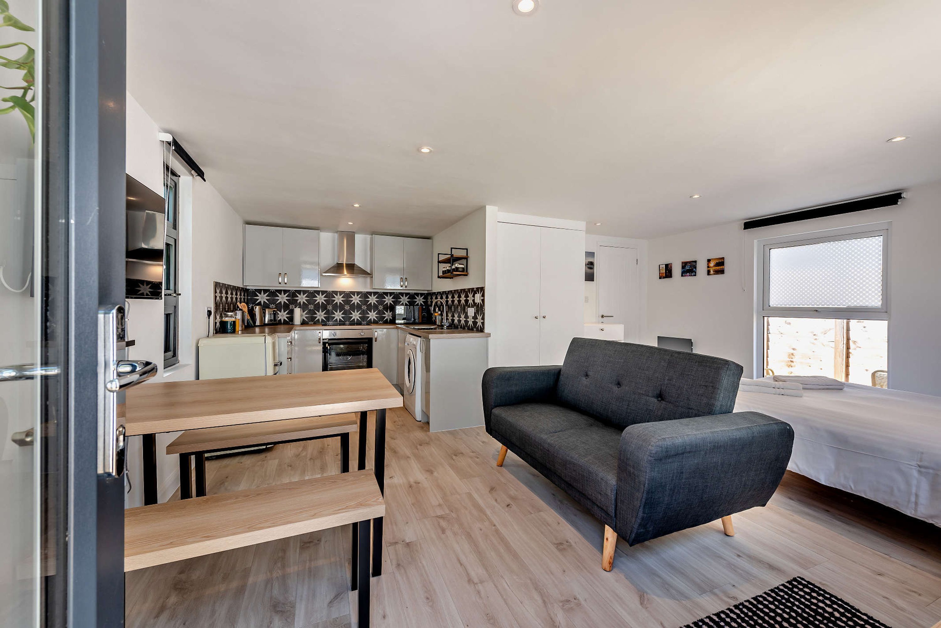 Un espace de vie compact comprenant un coin cuisine, un coin repas, un canapé et un lit.