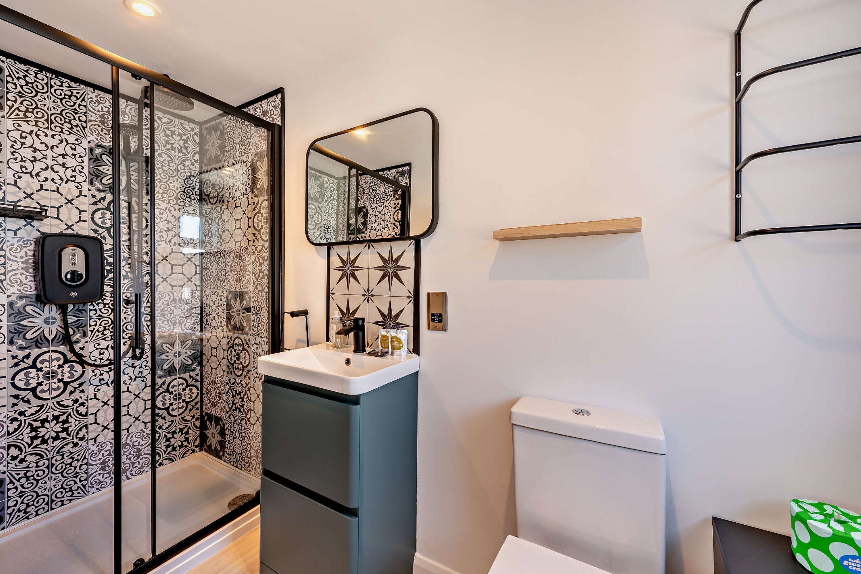 A bathroom with a glass shower enclosure, a white sink with a mirror above it, and a toilet.