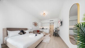 Ein modernes Hotelzimmer mit einem großen Bett, einem Schreibtisch, einer Küchenzeile und einem Badezimmer.