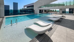 A rooftop pool with clear blue water, modern lounge chairs, and a view of city buildings. - Free Housekeeping Visits During Your Stay - Stayshort - Vibrant 1-bedroom Apartment at 1 Residences West in Za Abeel (Dubai)