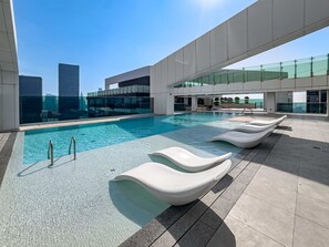 A rooftop pool with clear blue water, modern lounge chairs, and a view of city buildings. - Free Housekeeping Visits During Your Stay - Stayshort - Vibrant 1-bedroom Apartment at 1 Residences West in Za Abeel (Dubai)