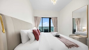 Een hotelkamer met een groot bed, een nachtkastje, een spiegel en uitzicht op de stad.