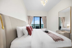 A hotel room with a large bed, a bedside table, a mirror, and a view of the city. - Free Housekeeping Visits During Your Stay - Stayshort - Modern 1BR in Prime Business Bay - 4 Guests (Dubai)