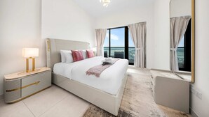 Een hotelkamer met een groot bed, een nachtkastje, een spiegel en uitzicht op de stad.