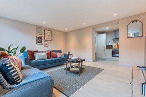 A living room with a sofa, a coffee table, and a patterned rug. - Hartley Hill Gem - Modern Apartment Near Leeds Centre (Leeds)