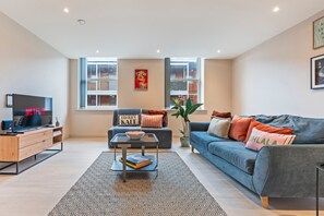 A modern living room with a sofa, coffee table, and TV. - Hartley Hill Gem - Modern Apartment Near Leeds Centre (Leeds)