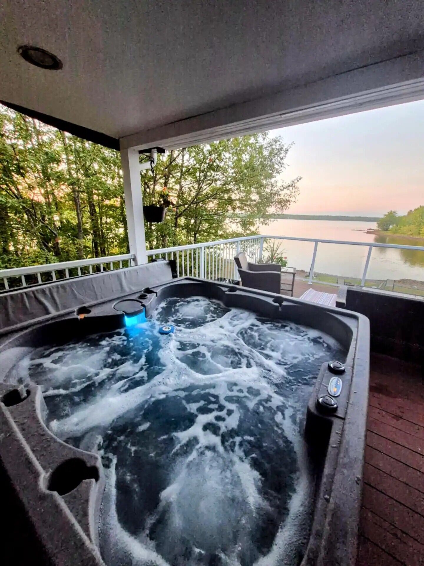 Een hottub op een terras met uitzicht op een meer en bomen.