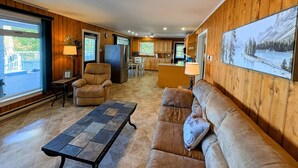 Ein gemütliches Wohnzimmer mit Kamin, Sofa, Couchtisch und einem großen Fenster.