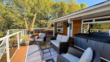 Terraza exterior con mobiliario de mimbre, una parrilla y un jacuzzi.