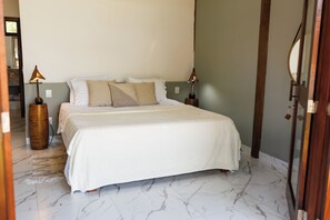 A bedroom with a large bed, two bedside lamps, and a marble floor.