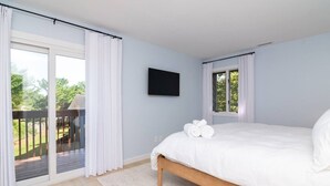 Een slaapkamer met een bed, een televisie en uitzicht op een terras.