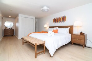 Une chambre à coucher comprenant un lit, des tables de chevet, un banc, une armoire et une œuvre d’art murale.