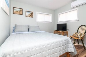 A bedroom with a bed, a television on a side table, and two windows. - Beach Block 3BR Home - Walk to Beach, Dining & Bars (Dewey Beach)