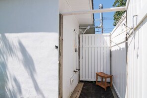 A narrow outdoor space with a white fence, a small wooden bench, and a door leading to a building. - Beach Block 3BR Home - Walk to Beach, Dining & Bars (Dewey Beach)