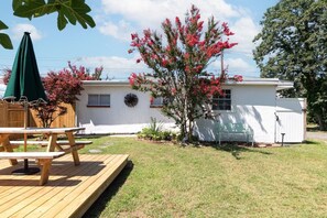 A residential property with a wooden deck, a white garage, and a tree with pink flowers. - Beach Block 3BR Home - Walk to Beach, Dining & Bars (Dewey Beach)