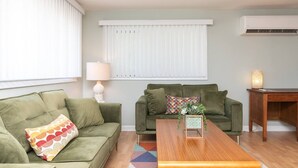 Una sala de estar con dos sofás verdes, una mesa de centro de madera y una lámpara.