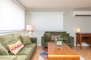 A living room with two green sofas, a wooden coffee table, and a lamp. - Beach Block 3BR Home - Walk to Beach, Dining & Bars (Dewey Beach)