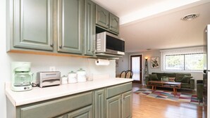 Una cocina con microondas, tostadora y cafetera sobre la encimera.
