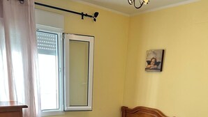 A bedroom with a bed, a dresser, a window with blinds, and a wall-mounted picture. - Los Niños Apartment (Conil de la Frontera)