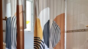 A bathroom with a toilet, bidet, and a shower curtain with abstract patterns. - Los Niños Apartment (Conil de la Frontera)