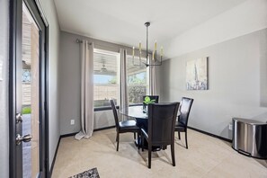 Een eetruimte met een tafel, stoelen, een kroonluchter en een schilderij aan de muur.