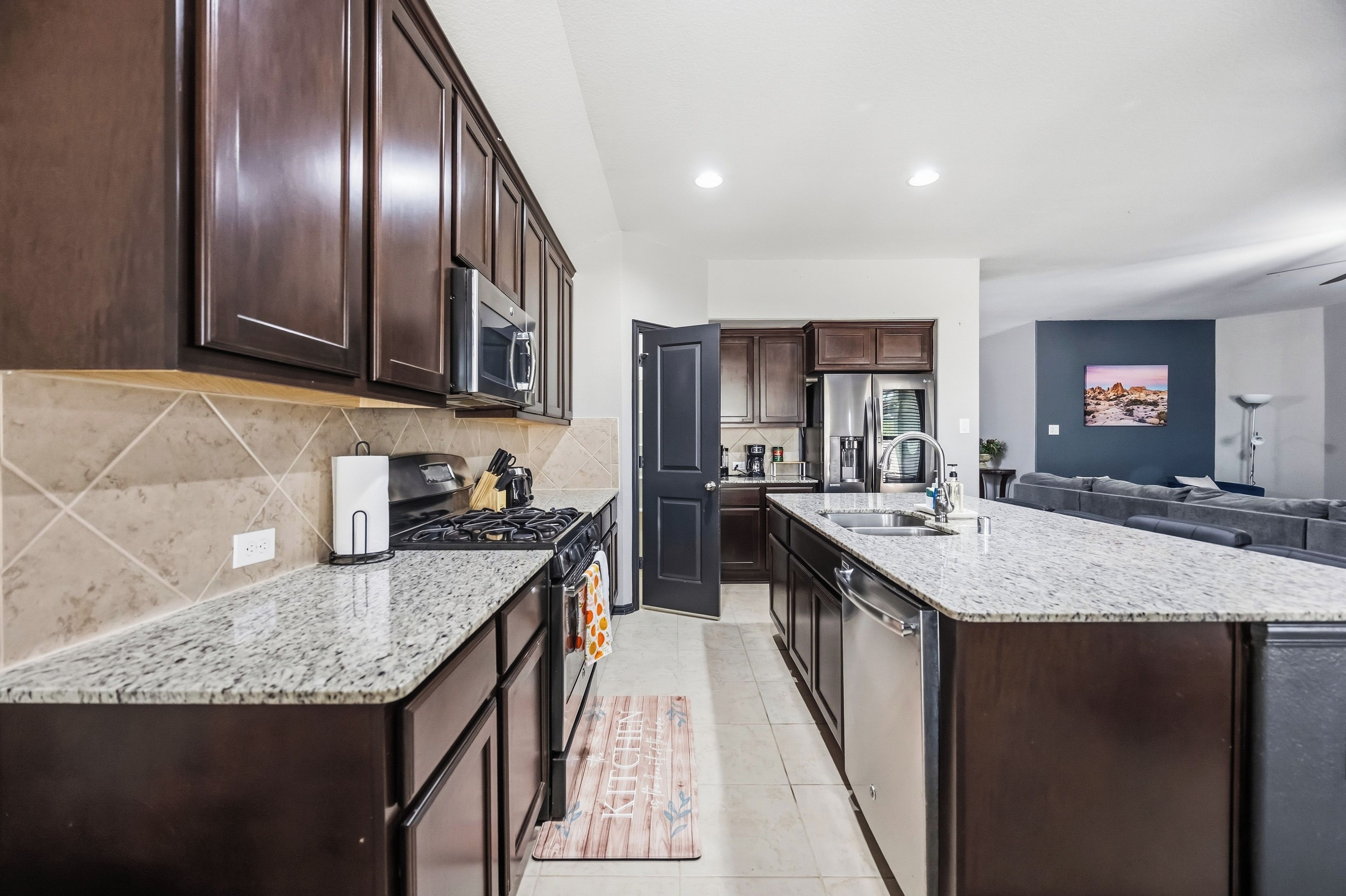 A modern kitchen with dark wood cabinets, stainless steel appliances, and a granite countertop.