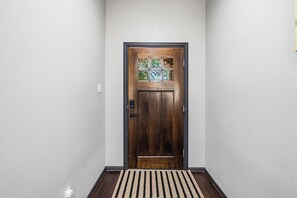 Een houten deur met een ruit en een deurmat bij de ingang.