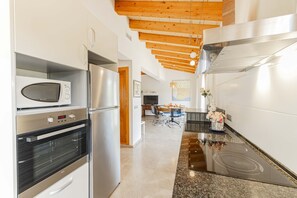 Eine moderne Küche mit Edelstahlgeräten, einer Arbeitsplatte aus Granit und einer Holzbalkendecke.