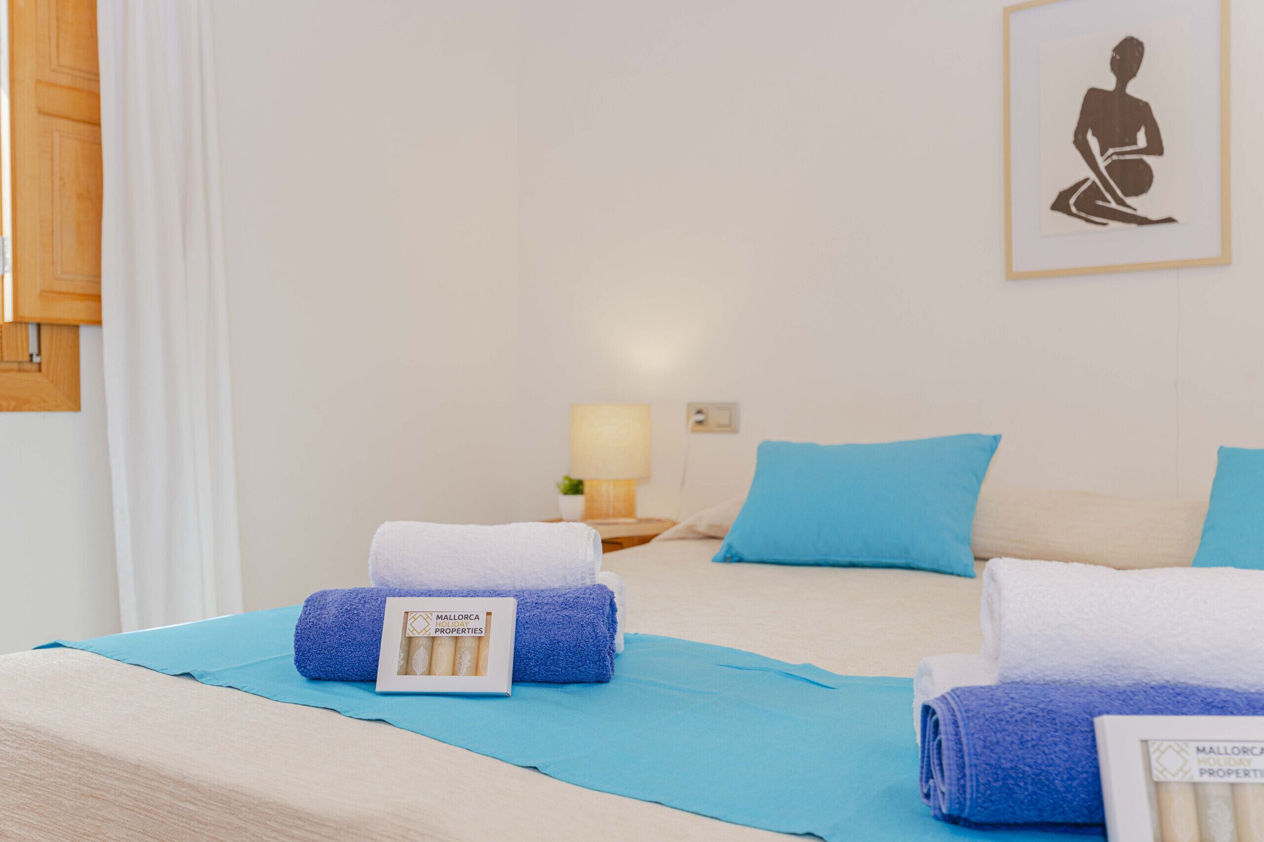 Une chambre d’hôtel avec un lit, deux oreillers, une table de chevet avec une lampe et un tableau encadré au mur.