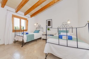 A bedroom with two beds, a window, a nightstand, and a wall-mounted lamp. - The <b>Villa Son Fornes</b> has 3 bedroom(s) and capacity for 6 people. (Buger)