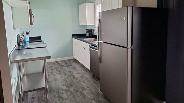 A compact kitchen with a refrigerator, sink, and a coffee maker.