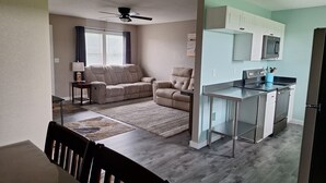 A compact living space with a kitchenette, a ceiling fan, a sofa, and a dining area.