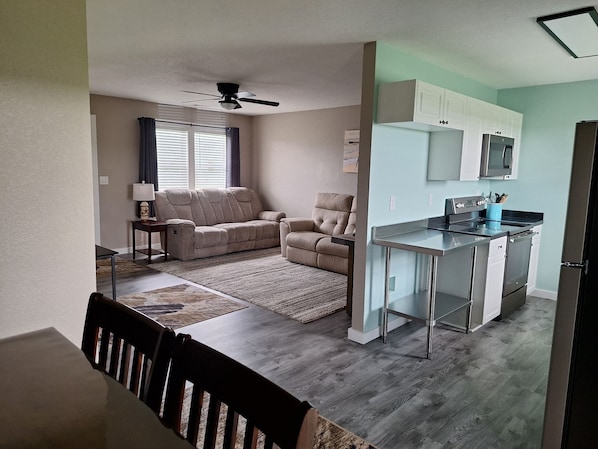 Un espacio habitable compacto con kitchenette, ventilador de techo, sofá y comedor.