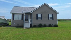 A single-story house with a front porch, a garage, and a boat parked outside.