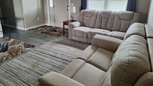 A living room with a beige sofa, a patterned rug, and a door in the background.
