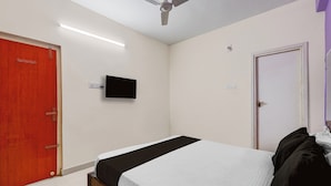 Ein Schlafzimmer mit einem Bett, einem Deckenventilator, einem Fernseher und einer Tür.
