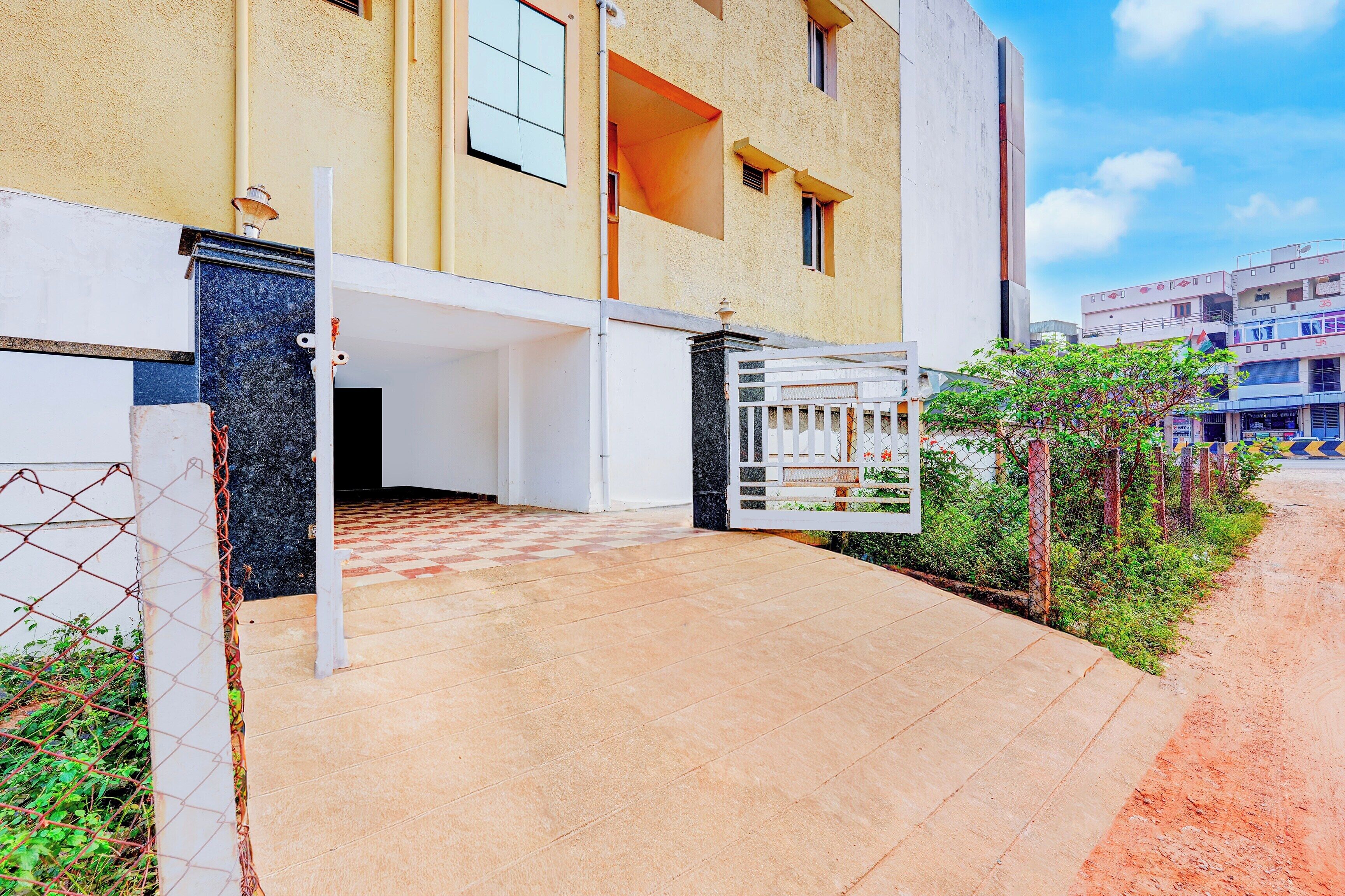 A multi-story residential building with a gated entrance, a covered parking area, and a visible staircase leading to the entrance.
