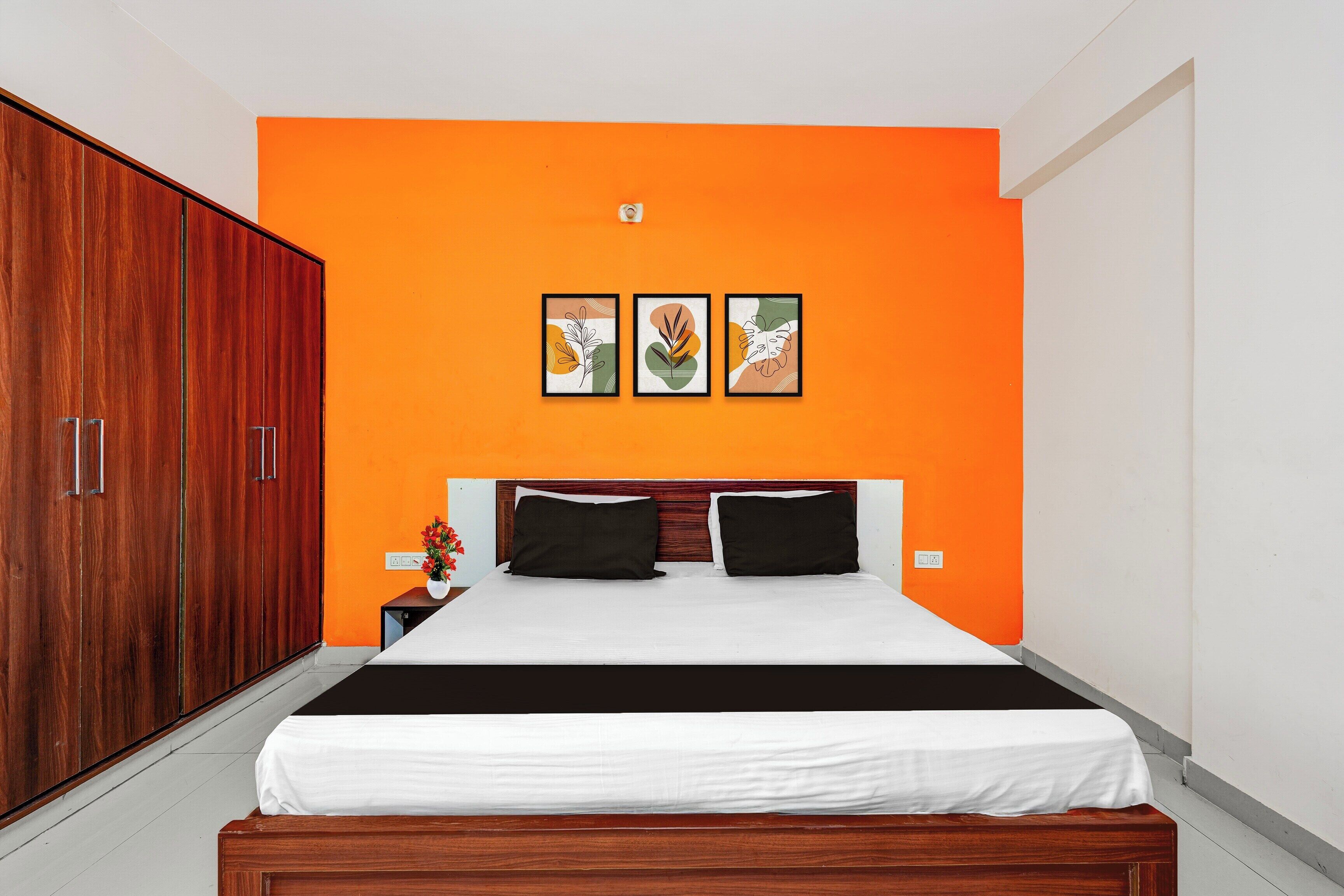 Un dormitorio con un armario grande, una cama con ropa de cama blanco y negro, y tres obras de arte enmarcadas en la pared.