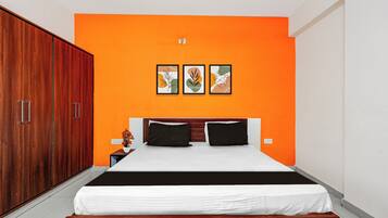 Un dormitorio con un armario grande, una cama con ropa de cama blanco y negro, y tres obras de arte enmarcadas en la pared.