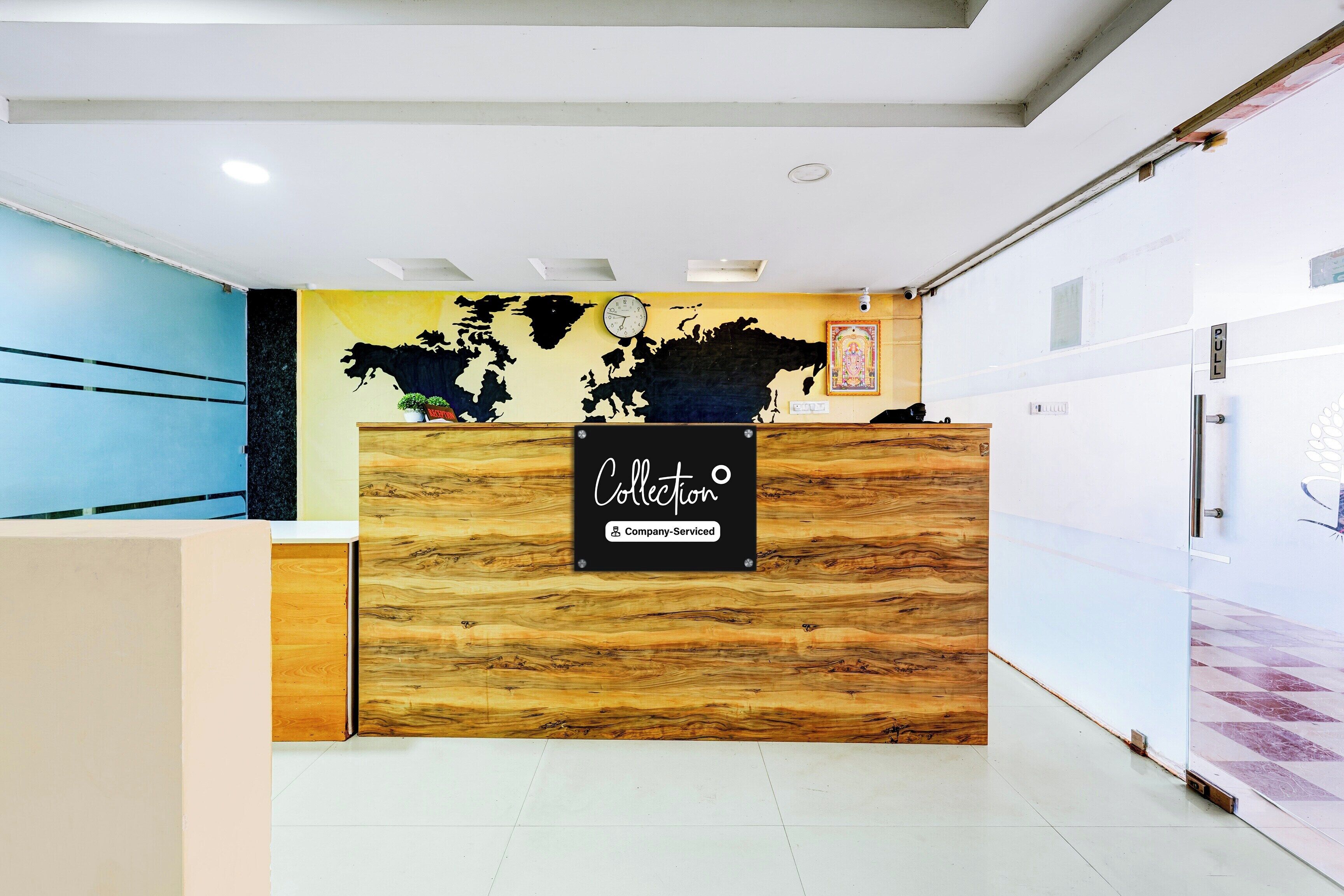 A reception desk with a world map mural, a clock, and a sign indicating it's company-serviced.