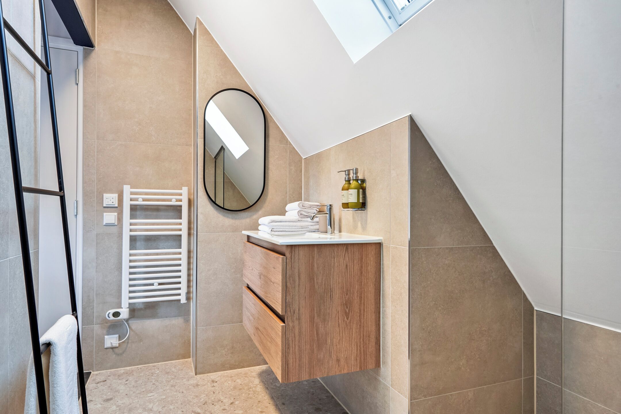 A modern bathroom with a wooden vanity, a mirror, and a towel rack.