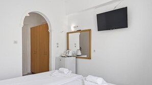 A hotel room with a bed, a TV mounted on the wall, a mirror, and a wooden door. - Bed and Breakfast 'The Kavos Sandy Inn-Double Room' with Shared Pool, Wi-Fi and Air Conditioning (Kavos)
