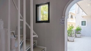 A staircase leading to a landing with a small window and a door with a sign above it. - Bed and Breakfast 'The Kavos Sandy Inn-Double Room' with Shared Pool, Wi-Fi and Air Conditioning (Kavos)