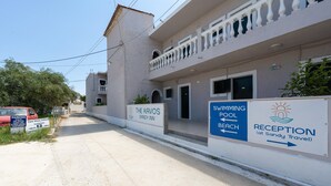 A building with a reception sign, a swimming pool, and a beach sign. - Bed and Breakfast 'The Kavos Sandy Inn-Double Room' with Shared Pool, Wi-Fi and Air Conditioning (Kavos)